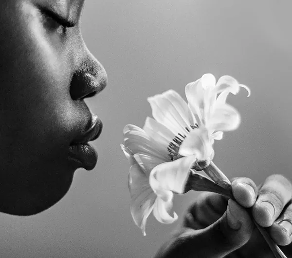 Black and white photo of a woman smelling a flower, from the Your Brain on Art website